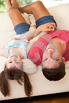 Father Lying Upside Down On Sofa With Daughter