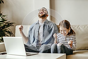 Father male businessman working at a computer with child daughter, won victory, success, triumph