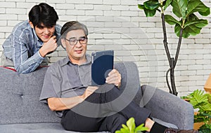 Father man and his son sit on sofa talking chatting on video call