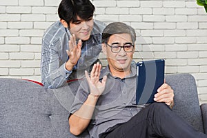 Father man and his son sit on sofa talking chatting on video call