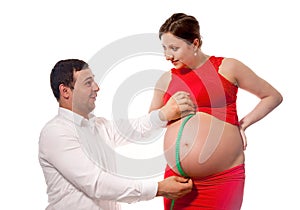 Father with measuring tape, checking belly size of pregnat wife