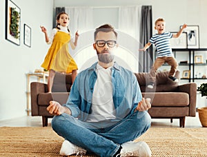 Father meditating in room with playful kids