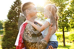 Father in military uniform with American flag holding his little daughter