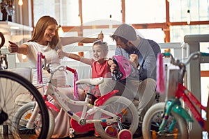 Father and mother buying new bicycle and helmets for little girl