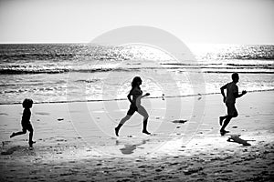 Father, mother and child run on the beach. Concept healthy family lifestyle. Summer people running, parents and child on