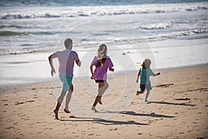 Father, mother and child running jogging on the beach. Concept healthy family lifestyle. Summer people vacation at sea.
