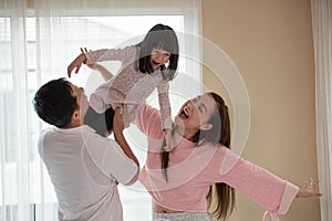 Father, mother and children daughters are having fun and playing in bedroom, happy Asian family