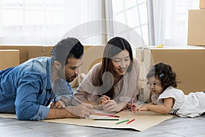 Father Mother and daughter drawing and coloring with colored pencils lying down on the floor. Happy family moment in the house.Art