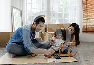 Father Mother and daughter painting coloring with watercolor on the wooden house mock up. Sitting on the floor in living room.