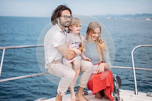 Father, mother and daughter sailing on yacht at the sea