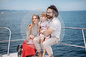 Father, mother and daughter sailing on yacht at the sea