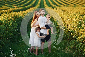 Father, mother with daughter and son spending free time outdoors at sunny day time of summer