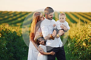 Father, mother with daughter and son spending free time outdoors at sunny day time of summer