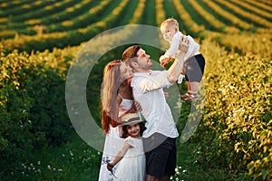 Father, mother with daughter and son spending free time outdoors at sunny day time of summer