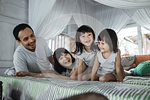 Father, mother and daughters relaxing together on bed