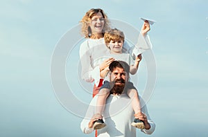 Father mother and his son playing outdoors. Summer ration. Cute little boy is holding paper airplane. Happy family