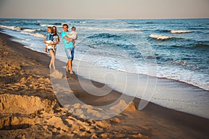 Father, mother and kids walking along the beach, near the ocean, happy lifestyle family concept