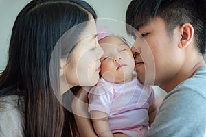 Father and mother kissing a little baby, Parenthood, Family concept