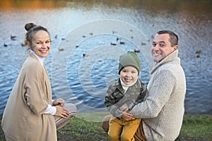 Father, mother and little son feeding ducks