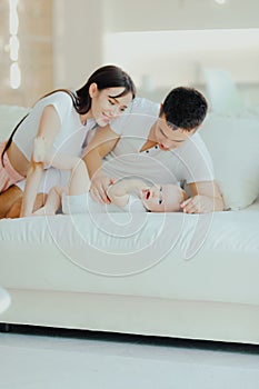 Father, mother and little son are relaxing on sofa in living room