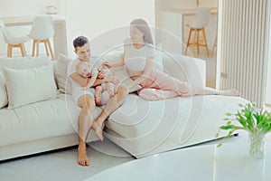Father, mother and little son are relaxing on sofa in living room