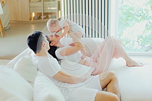 Father, mother and little son are relaxing on sofa in living room