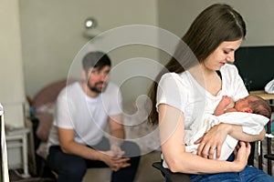 Father and mother with a newborn son sitting in the room