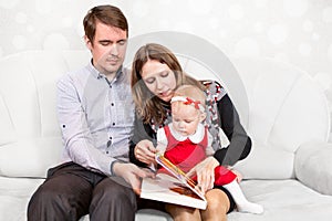 Father and mother opening book for baby reading