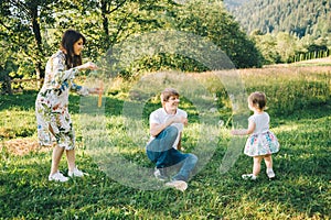 Father and mother play with his daughter with soapbubble