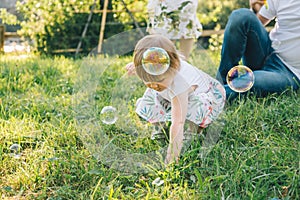 Father and mother play with his daughter with soapbubble