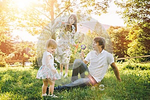 Father and mother play with his daughter with soapbubble