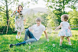 Father and mother play with his daughter with soapbubble