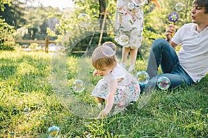 Father and mother play with his daughter with soapbubble