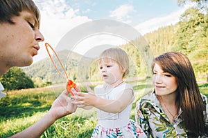 Father and mother play with his daughter with soapbubble