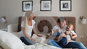 Father and mother playing with boy two years lying in bed