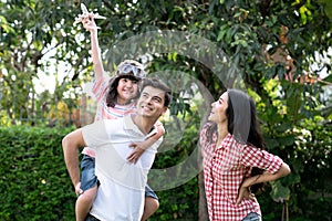 Father and mother playing with children outside.