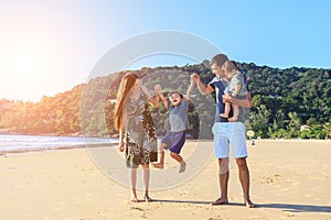 Father and mother playing with son on the beach at the sunset ti