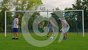 Father, mother, son and baby girl playing soccer for fun outdoors in park. Happy family. Parents and children play