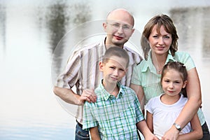 Father, mother, son and daughter on pond backgroun