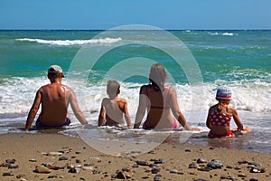 Father, mother, son and daughter sitting on beach
