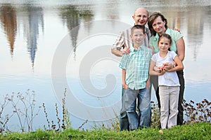 Father, mother, son and daughter staying near pond
