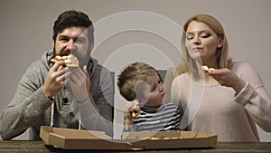 Father mother and son eating pizza at home. Kid boy with favorite food. Happy family food concept, happy hungry man eat