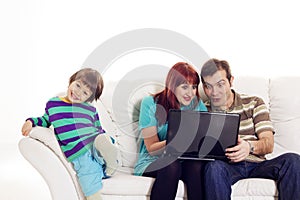 Father, mother and son sitting on the sofa with notebook