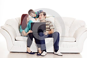 Father, mother and son sitting on the sofa with notebook