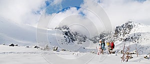 Father and mother with two small children in winter nature, playing in the snow.