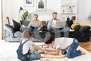 Father and mother working on the distance during quarantine. Parents work remotely with laptops sitting on the couch in