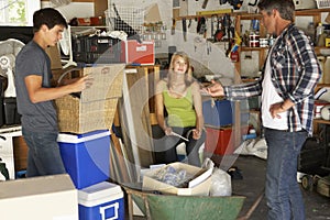 Father Organising Two Teenagers Clearing Garage For Yard Sale