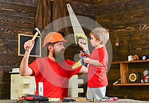 Father, parent with beard in protective helmet teaching son to use different tools in school workshop. Boy, child