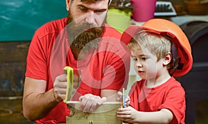 Father, parent with beard teaching little son to sawing while son play with toy saw. Educational games concept. Boy