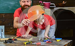 Father, parent with beard teaching little son to use different tools in school workshop. Boy, child busy play with